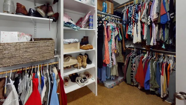 a view of walk in closet with clothes and shoes