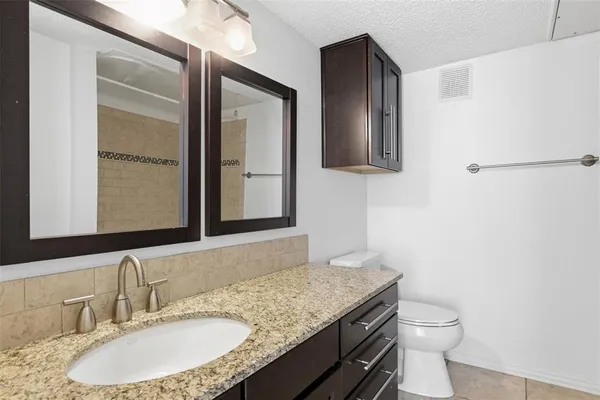 a bathroom with a granite countertop sink toilet and mirror