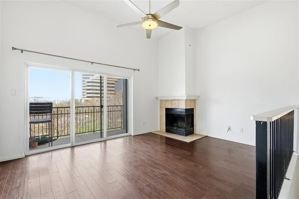 an empty room with wooden floor fireplace and windows