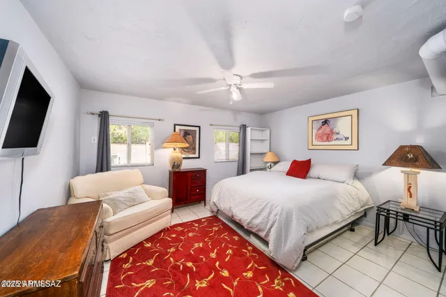 a spacious bedroom with a bed a couch and a flat tv screen on dresser