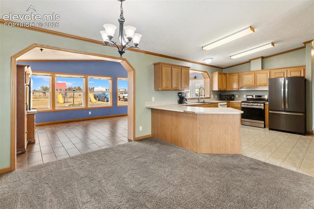 1350 South Calhan Highway Yoder, CO 80864 - Photo 18 of 45 Spacious kitchen featuring wood-finish cabinetry, stainless steel appliances, a light-toned countertop, and a breakfast bar