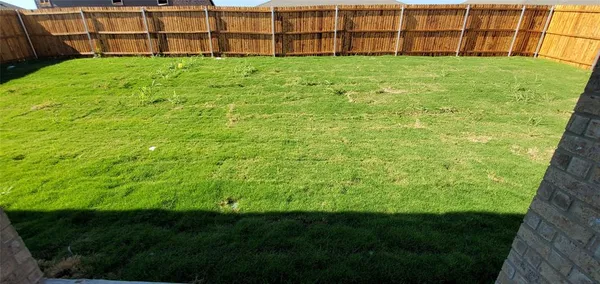 a view of a backyard with plants and wooden fence