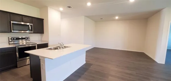 a kitchen with a sink and a stove top oven with wooden floor