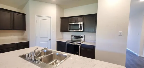 a kitchen with stainless steel appliances kitchen island granite countertop a refrigerator stove and sink