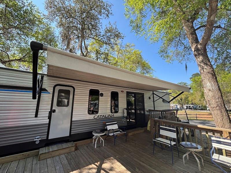 14403 Northeast 252nd Ct Road, Unit 128 Fort McCoy, FL 32134 - Photo 3 of 23 a view of a patio with table and chairs a couches and potted plants with wooden floor and fence
