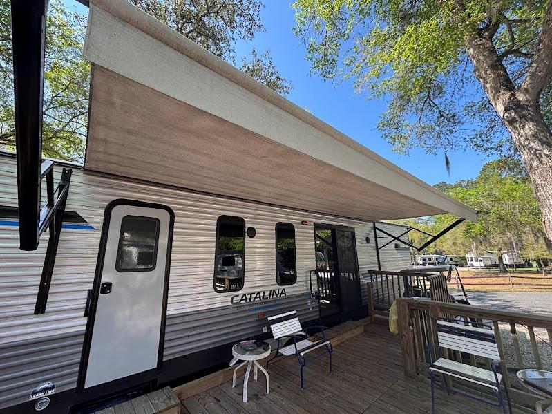 14403 Northeast 252nd Ct Road, Unit 128 Fort McCoy, FL 32134 - Photo 5 of 23 a view of a patio with table and chairs a barbeque with wooden floor and fence