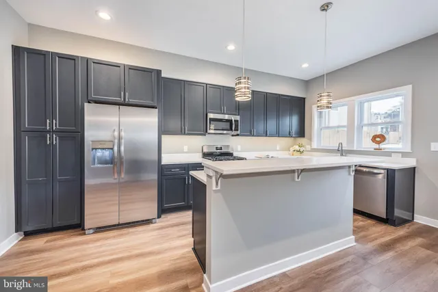 a kitchen with stainless steel appliances granite countertop a refrigerator a sink dishwasher a stove with wooden cabinets and floors