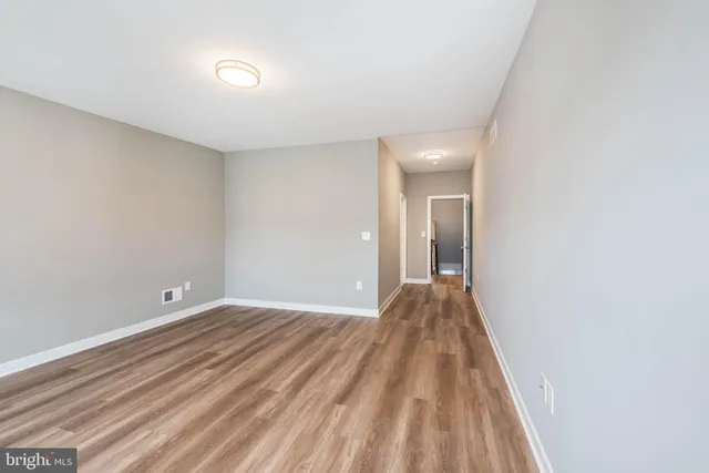 a view of a big room with wooden floor and windows
