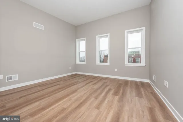 a view of an empty room with wooden floor and window