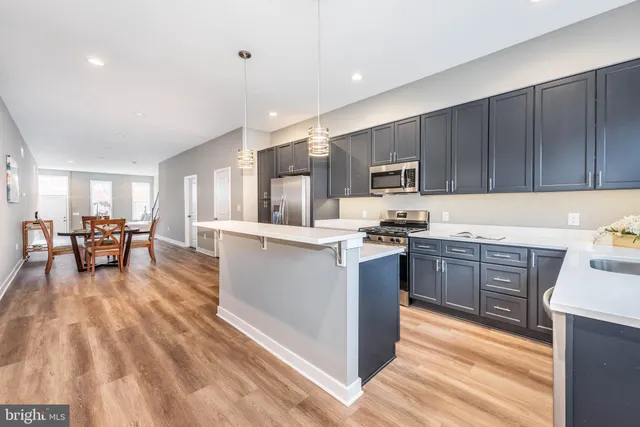 a kitchen with kitchen island granite countertop wooden cabinets a stove a microwave a island with a dining table and chairs