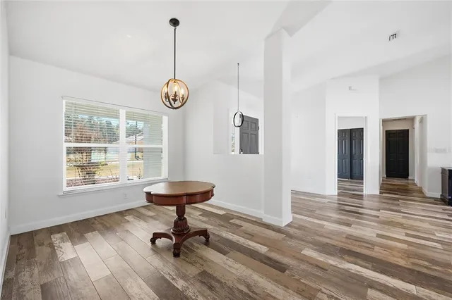 a view of an empty room with wooden floor and a kitchen