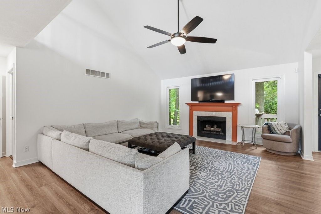 2323 Call Road Stow, OH 44224 - Photo 10 of 42 Vaulted ceiling with a ceiling fan, fireplace with a contrasting mantel, wood-finish flooring, and large windows offering natural light