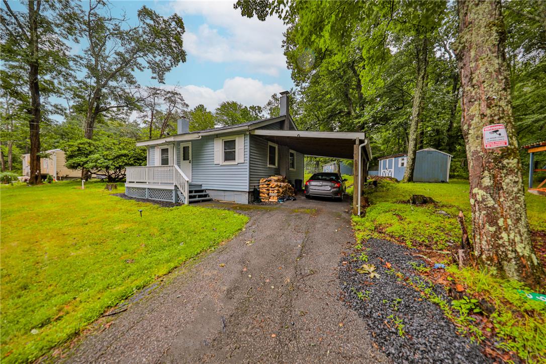 5599 Minks Pond Road Bushkill, PA 18324 - Photo 33 of 64 A charming light blue residence with a practical carport sits nestled amongst verdant trees.