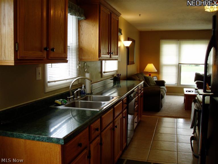 The updated galley kitchen has oak cabinets and ceramic tile flooring.