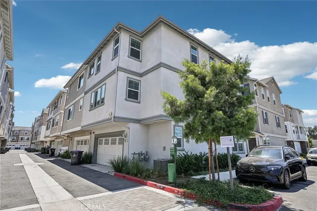 a view of a white building among the street with palm trees