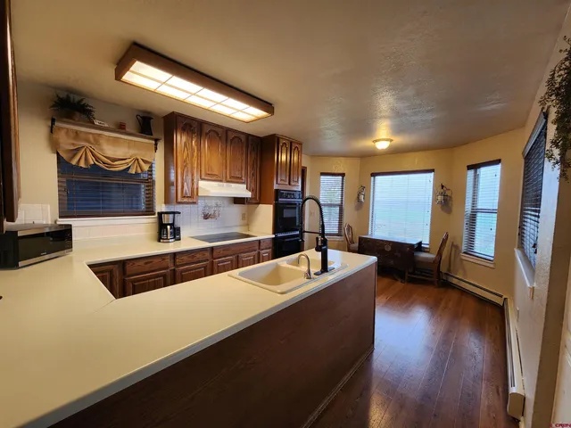 a large kitchen with a large counter top space a sink and wooden floor