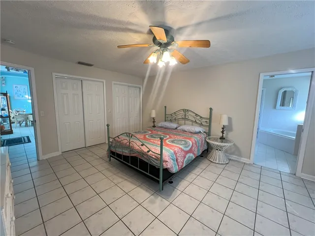 a spacious bedroom with a bed and a chandelier fan