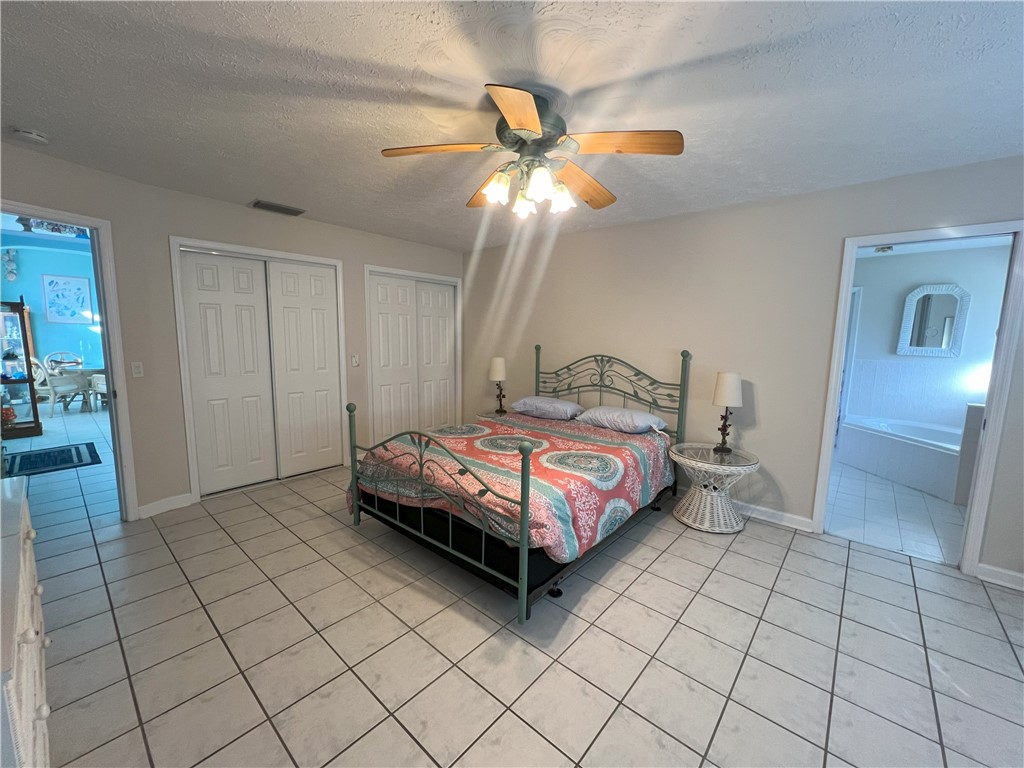 401 Coply Terrace Sebastian, FL 32958 - Photo 18 of 36 a spacious bedroom with a bed and a chandelier fan
