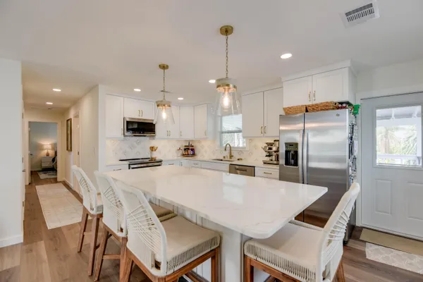 a kitchen with stainless steel appliances kitchen island a table chairs refrigerator and microwave