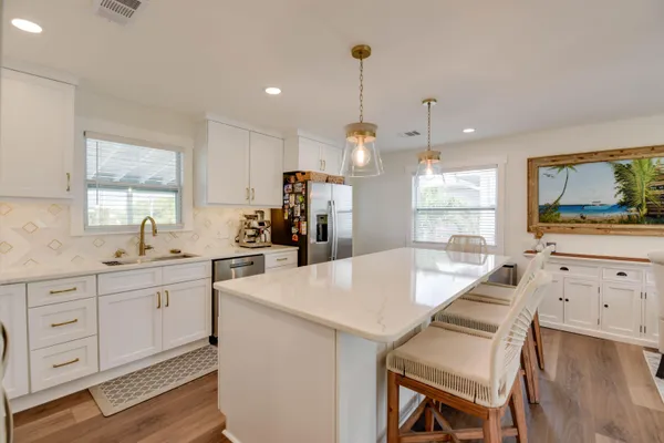 a kitchen with white cabinets and wooden floors