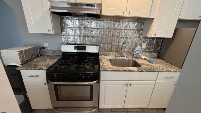 a kitchen with granite countertop a stove sink and cabinets