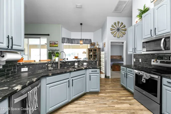 a kitchen with stainless steel appliances granite countertop a stove a sink and a microwave