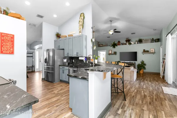 a kitchen with stainless steel appliances kitchen island granite countertop a refrigerator a stove top oven and a sink with cabinets