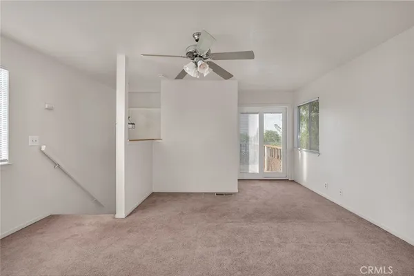 an empty room with chandelier fan and windows