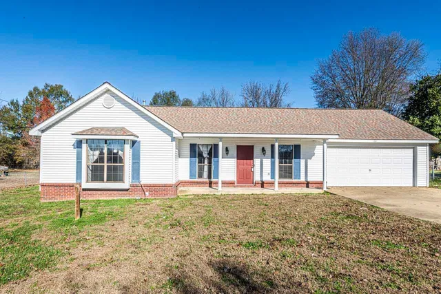 a front view of a house with a yard and trees
