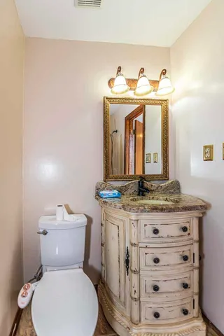 a bathroom with a granite countertop toilet sink and mirror