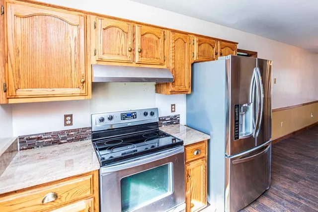 a kitchen with stainless steel appliances granite countertop a refrigerator and a stove top oven