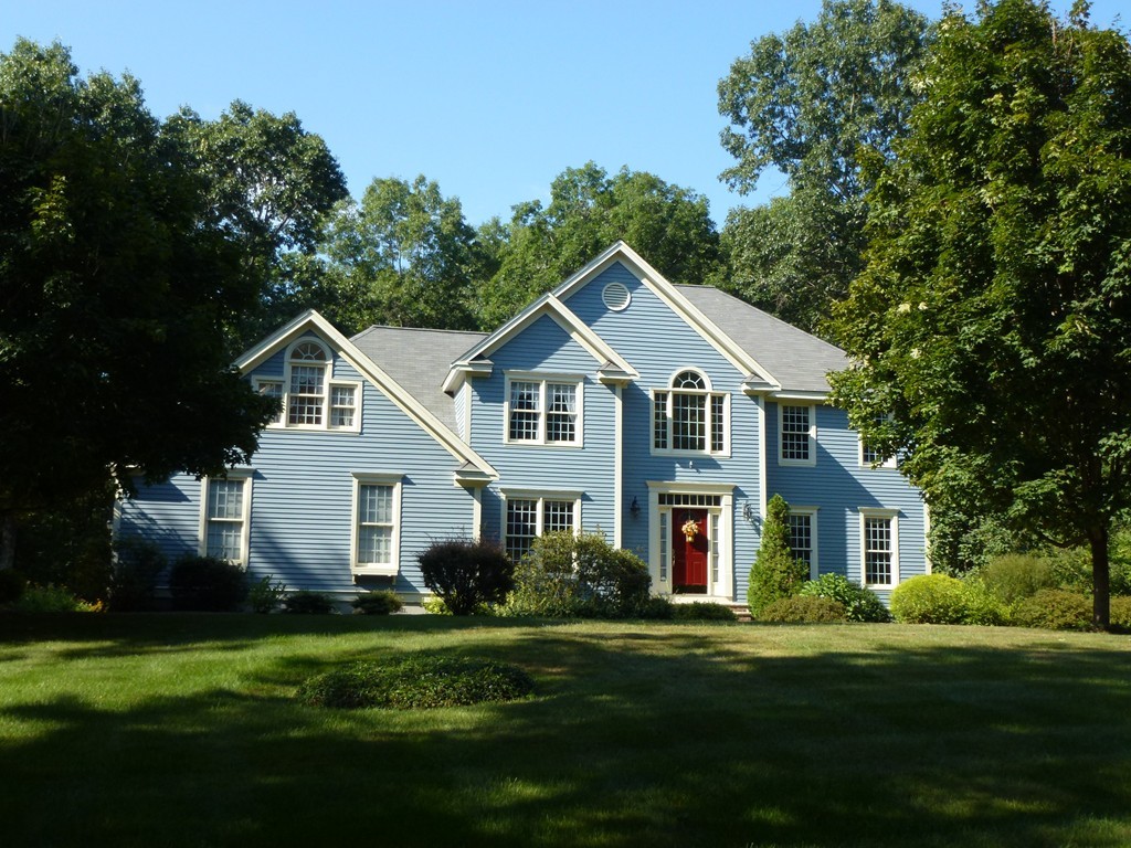 a front view of a house with a garden and trees