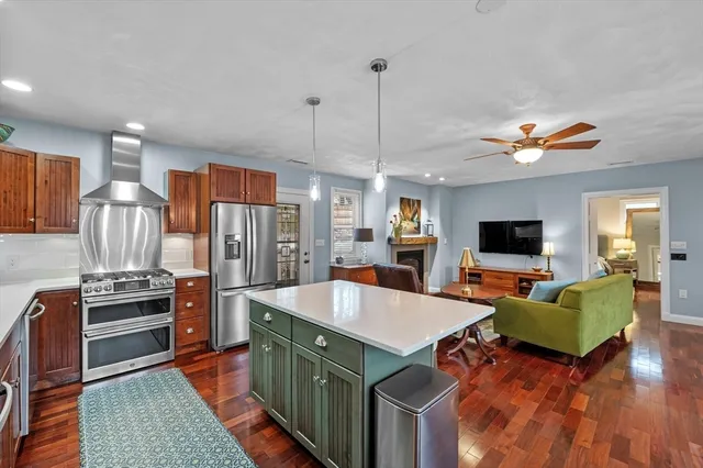 a living room with stainless steel appliances furniture fireplace and flat screen tv