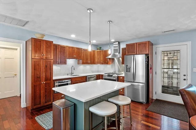 a kitchen with stainless steel appliances a refrigerator a sink a dining table and chairs