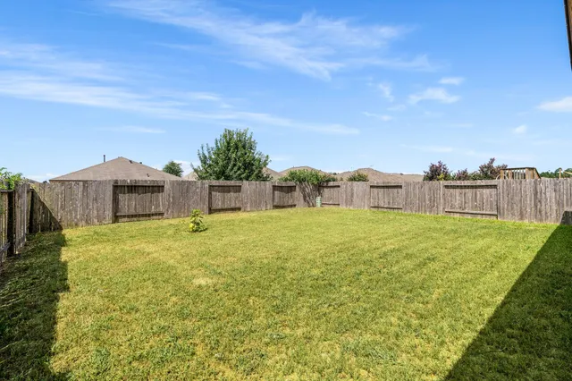 a backyard of a house with plants and wooden fence