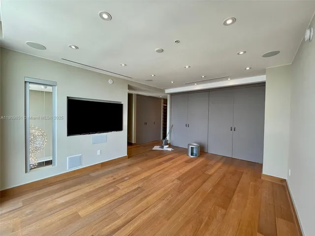 a view of an empty room with wooden floor and windows