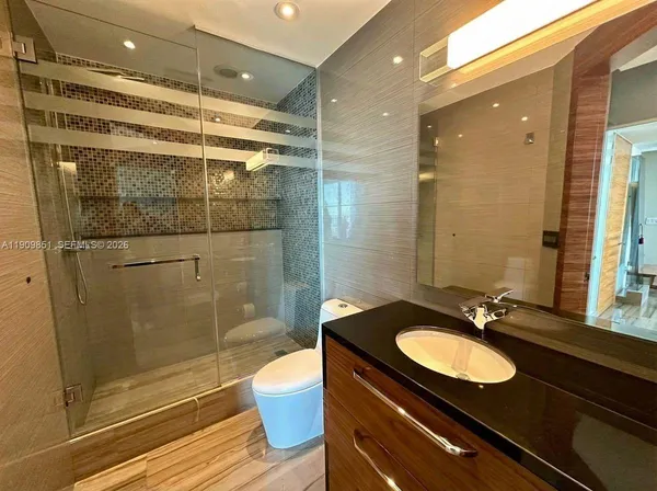 a bathroom with a sink shower and a mirror