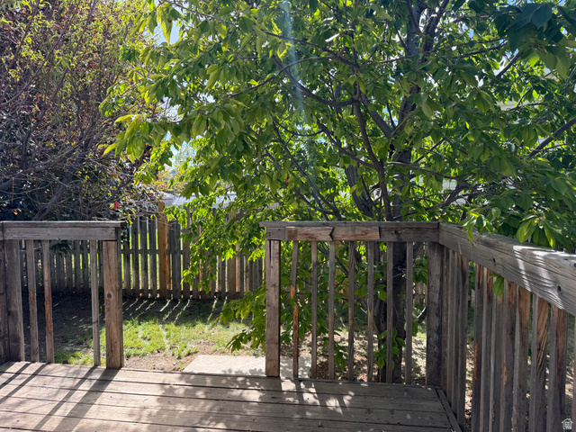 44 Wapiti Loop Hyrum, UT 84319 - Photo 4 of 18 Outdoor deck featuring wood construction, leading to a fenced backyard with mature trees and a grass area