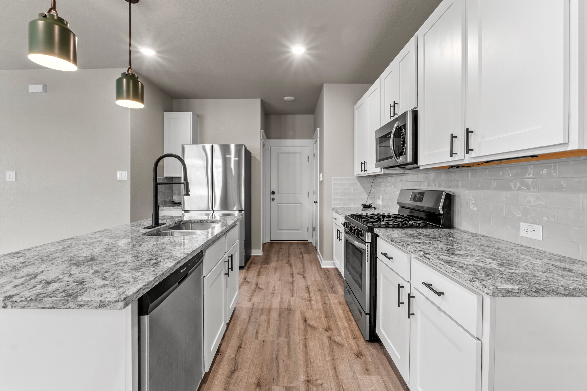 2251 Rocoso Trail Leander, TX 78641 - Photo 11 of 34 Gleaming stone countertops and stainless steel appliances elevate this modern, light-filled kitchen space.