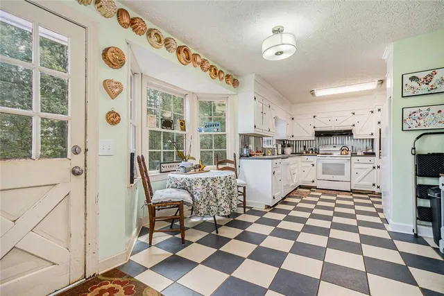 a kitchen with a checkered floor and white cabinets next to a window