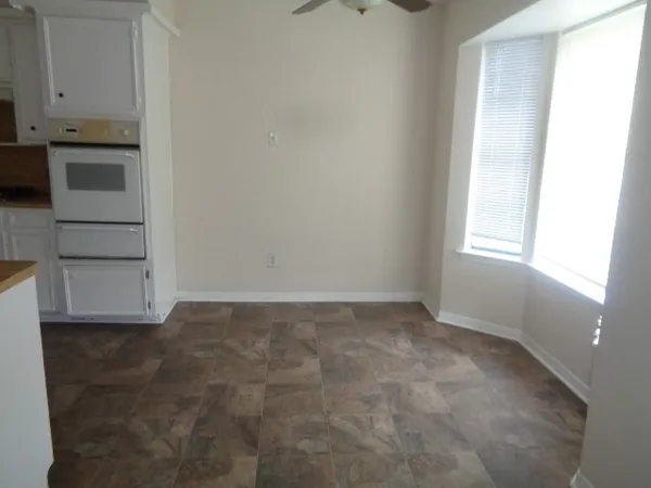 an empty room with wooden floor fire place and windows