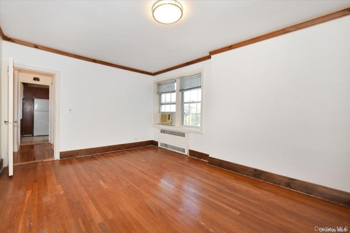 175-06 Devonshire Road, Unit 4M Queens, NY 11432 - Photo 12 of 18 a view of an empty room with wooden floor and a window