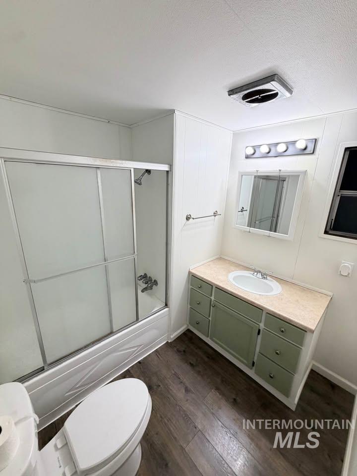 15881 Purple Sage Road, Unit 48 Caldwell, ID 83607 - Photo 6 of 17 Bathroom with vanity, dark wood-type flooring, bath / shower combo with glass door, and a textured ceiling