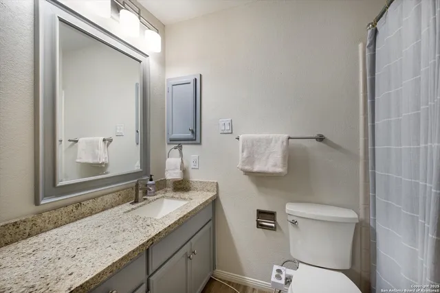 a bathroom with a granite countertop sink toilet and shower