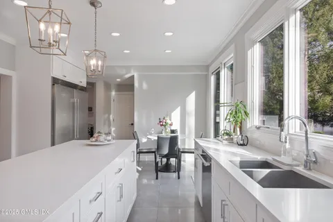 a large kitchen with kitchen island a large counter space a sink a center island stainless steel appliances and windows