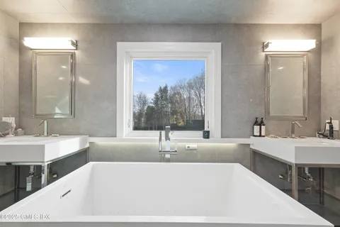 a bathroom with a bathtub a double vanity sink and mirror