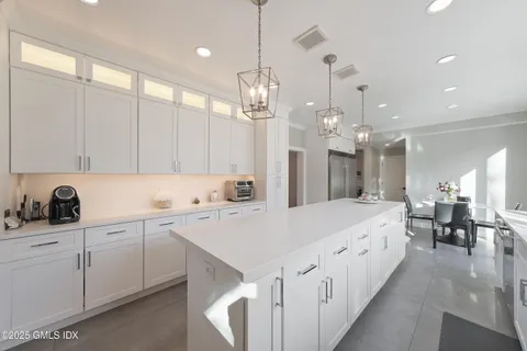 a large kitchen with kitchen island white cabinets and sink