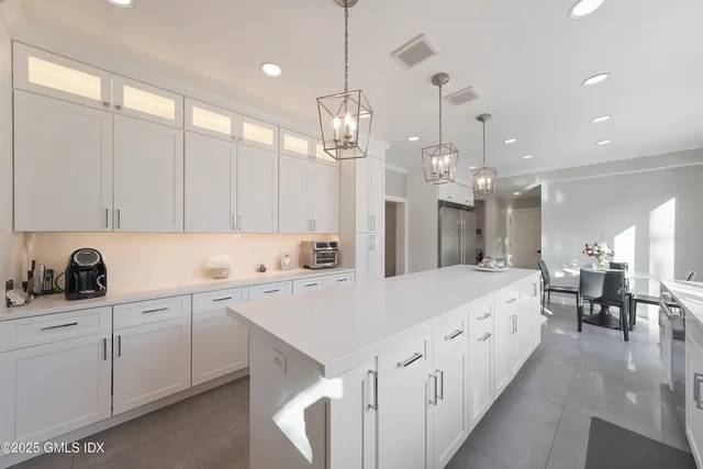 a large kitchen with kitchen island white cabinets and sink