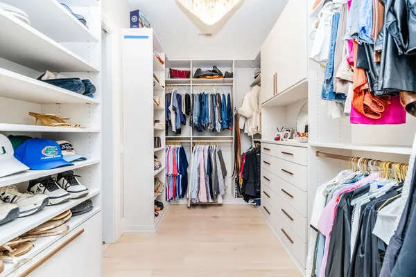a view of walk in closet with clothes and shoes