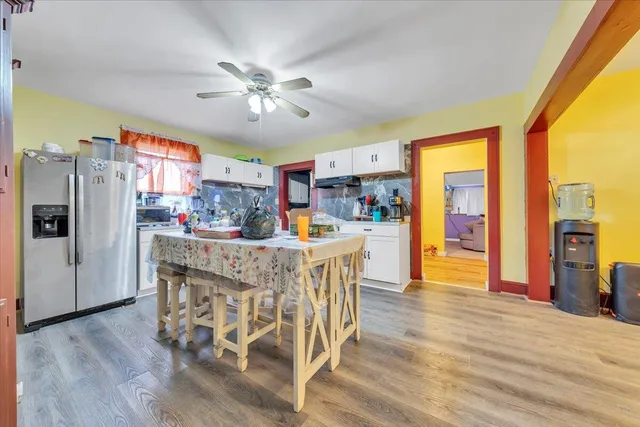 a dining area with stainless steel appliances granite countertop a refrigerator dining table and chairs with wooden floor